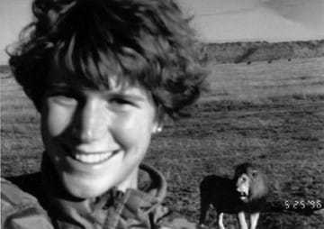 A black and white selfie of Leslianne Shedd with a lion in back.